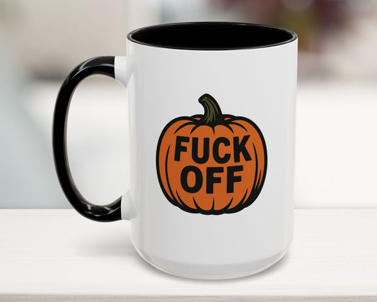 White mug with black interior and handle, featuring an orange pumpkin with text design on a blurred background.