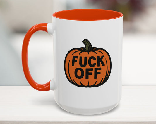 Mug with orange handle and pumpkin design featuring the text 'FUCK OFF' on a blurred background