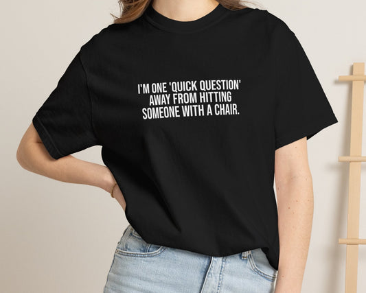 Person wearing a black t-shirt with text and denim shorts in a casual setting