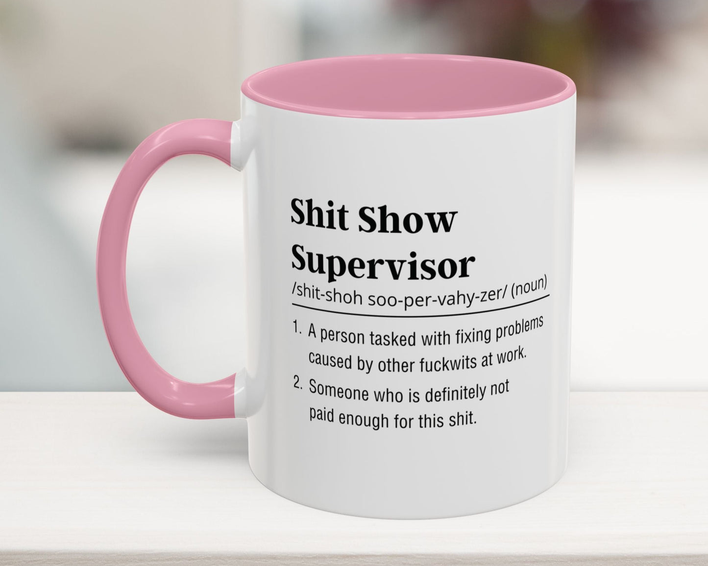 White mug with pink handle featuring humorous definition text on a blurred background