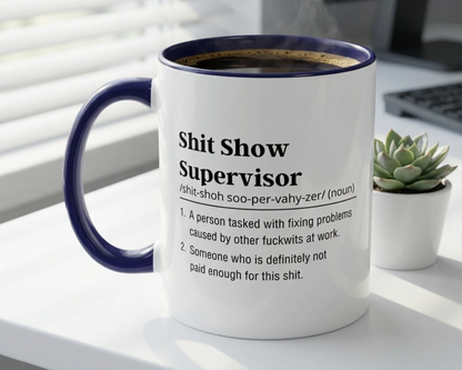 Mug with definition text on a desk with a plant and computer in the background