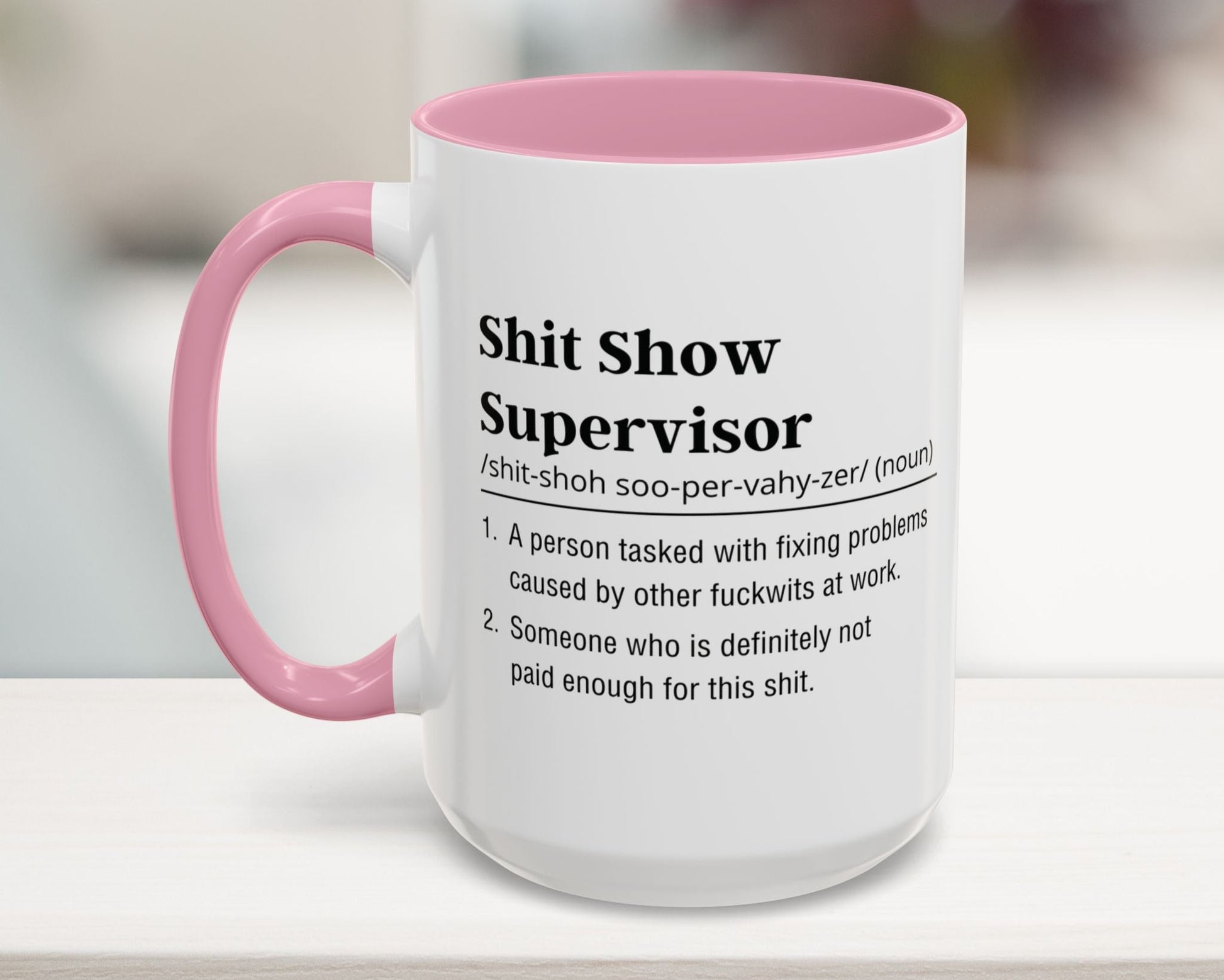Mug with pink handle and humorous definition text on a blurred background