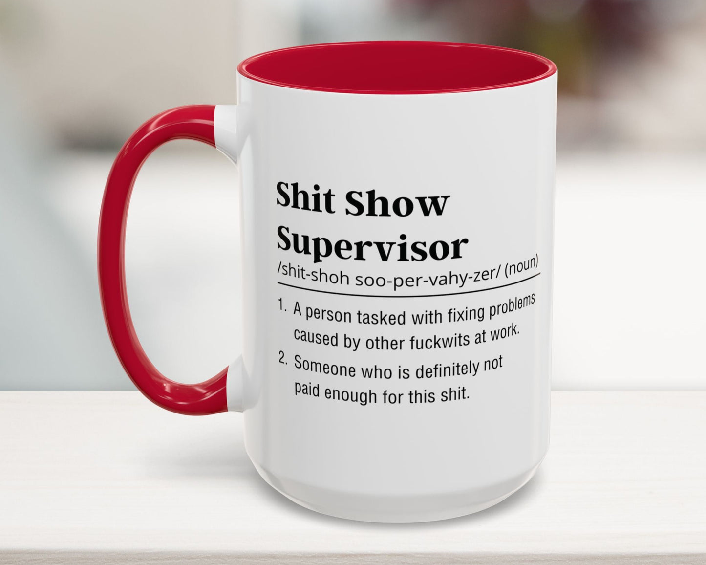 Mug with red interior and handle featuring humorous definition text on a blurred background
