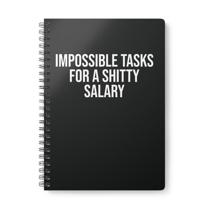 Black spiral-bound notebook with white text on a white background