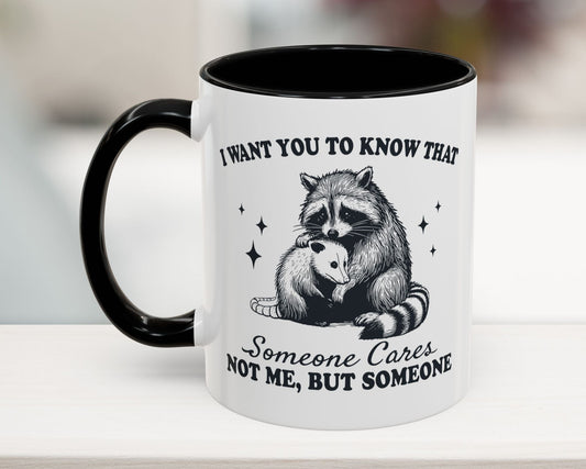 Black 11oz mug with raccoon hugging possum and text “Someone Cares, Not Me” – funny office coffee mug