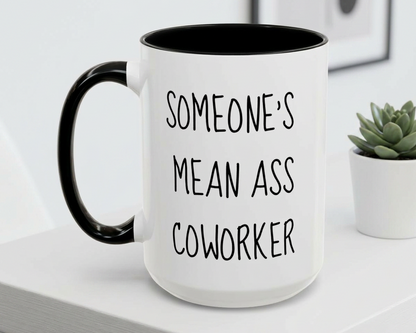 White mug with black interior and handle, featuring text, on a white surface with a plant in the background.
