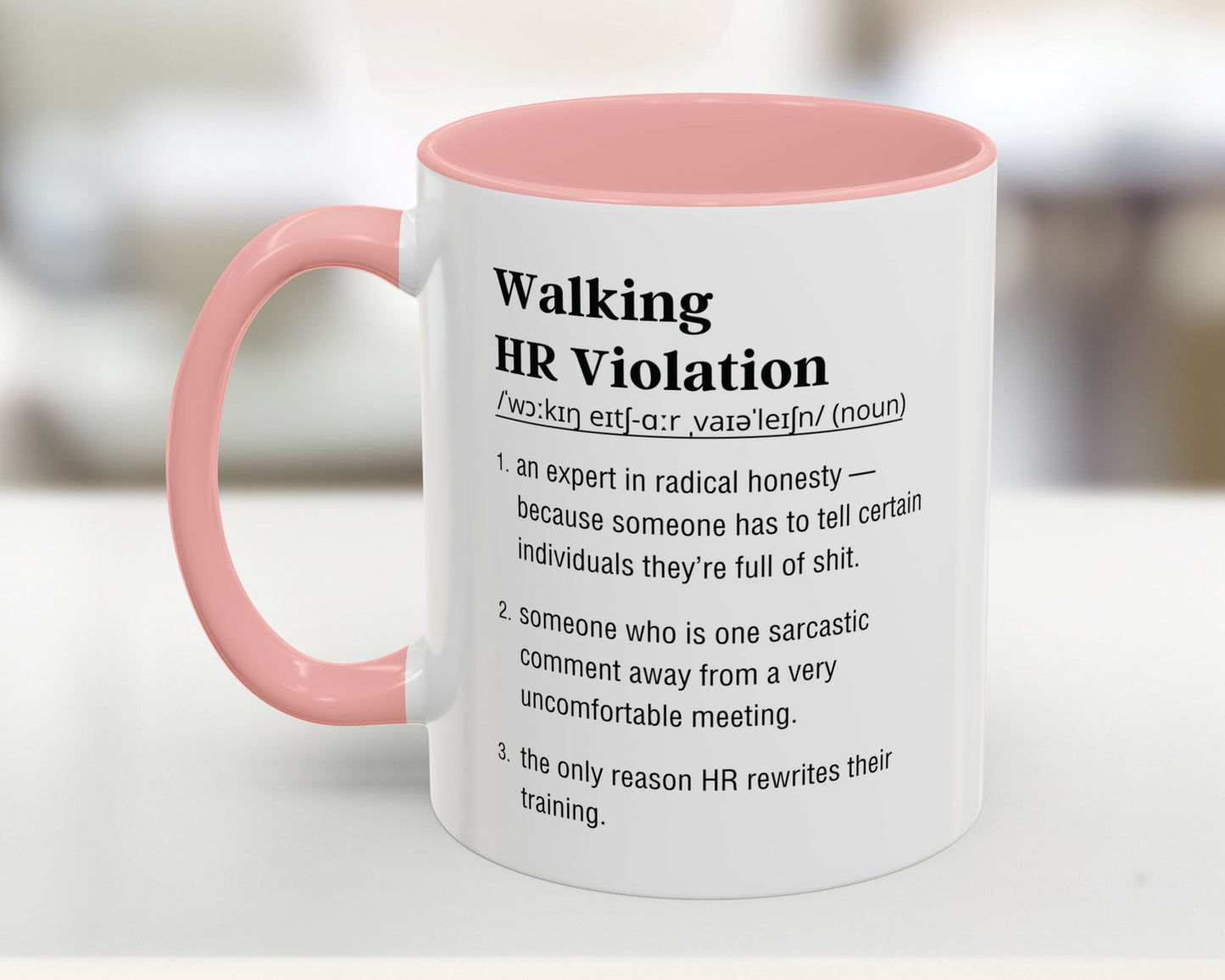 Mug with pink interior and handle featuring humorous definition text on a blurred background