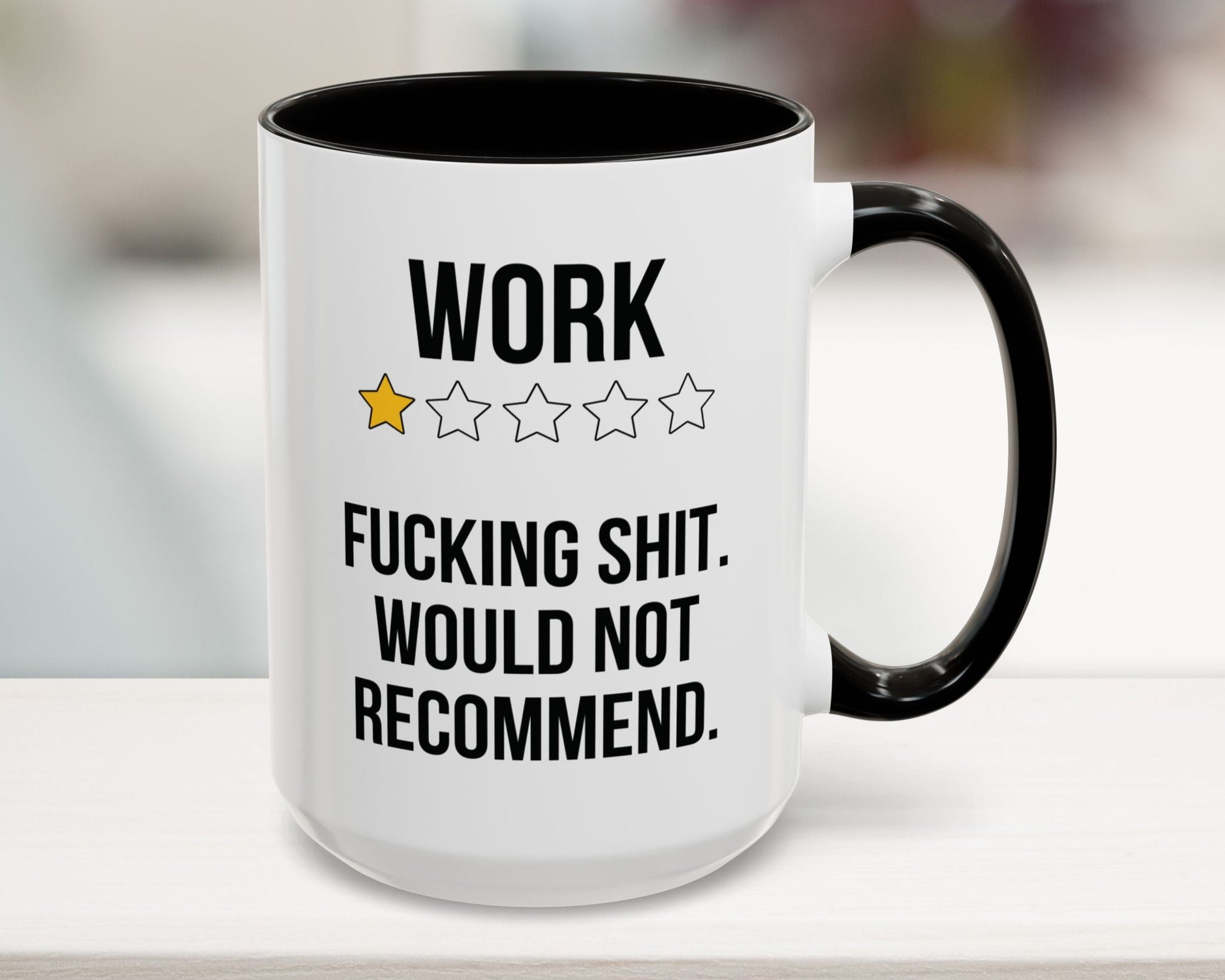 Mug with text 'WORK ★★★★ F***ING SHIT. WOULD NOT RECOMMEND.' on a blurred background