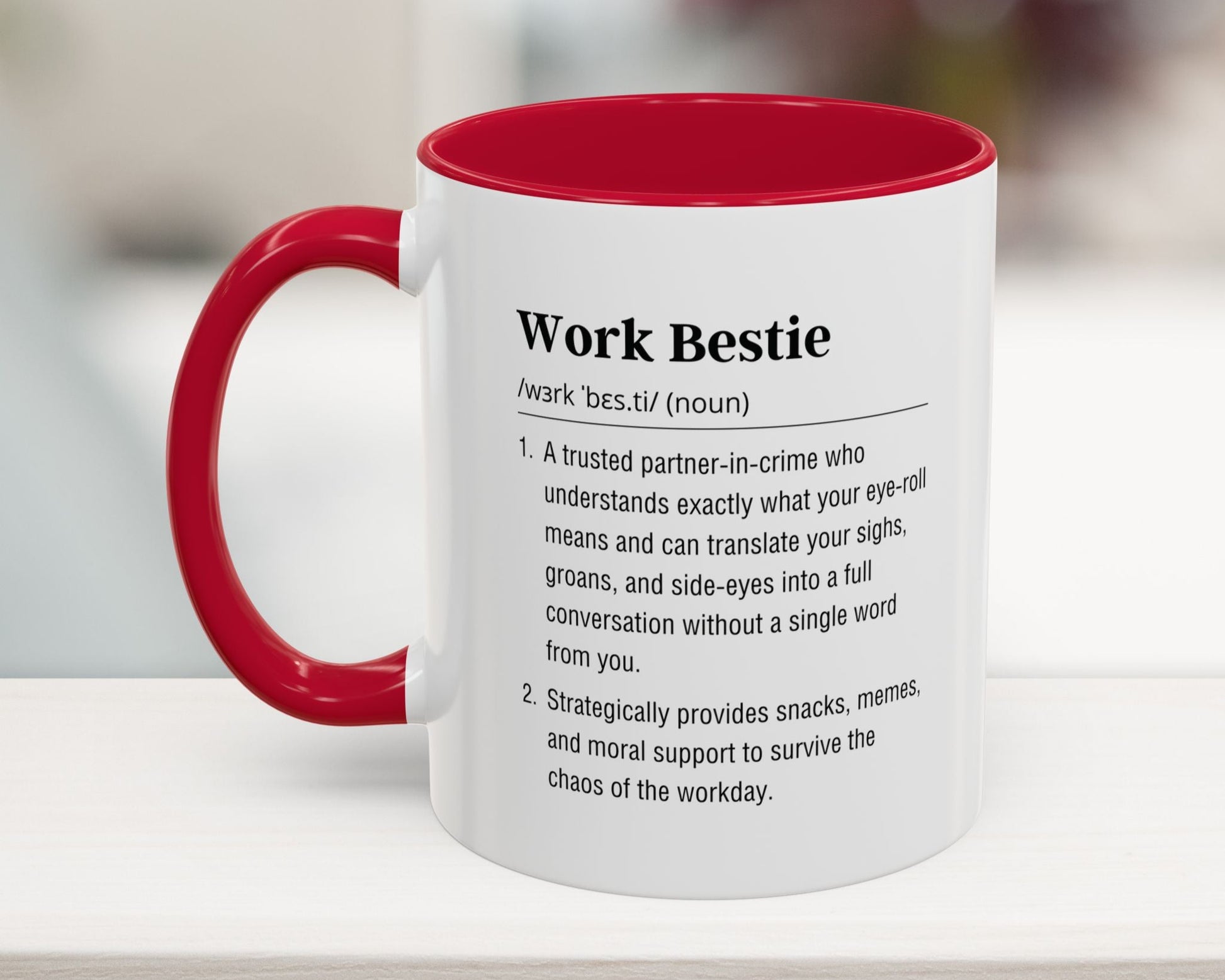 Mug with red interior and handle, featuring text definition on a blurred background